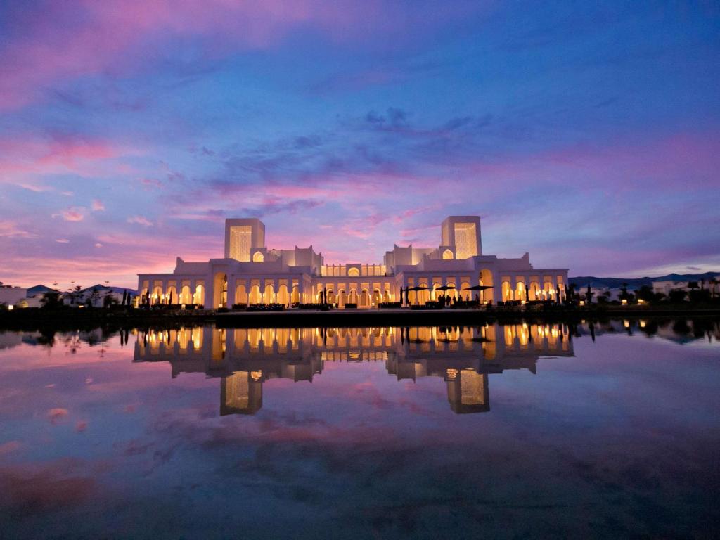 a large building with lights reflecting in a body of water at Banyan Tree Tamouda Bay in Fnidek