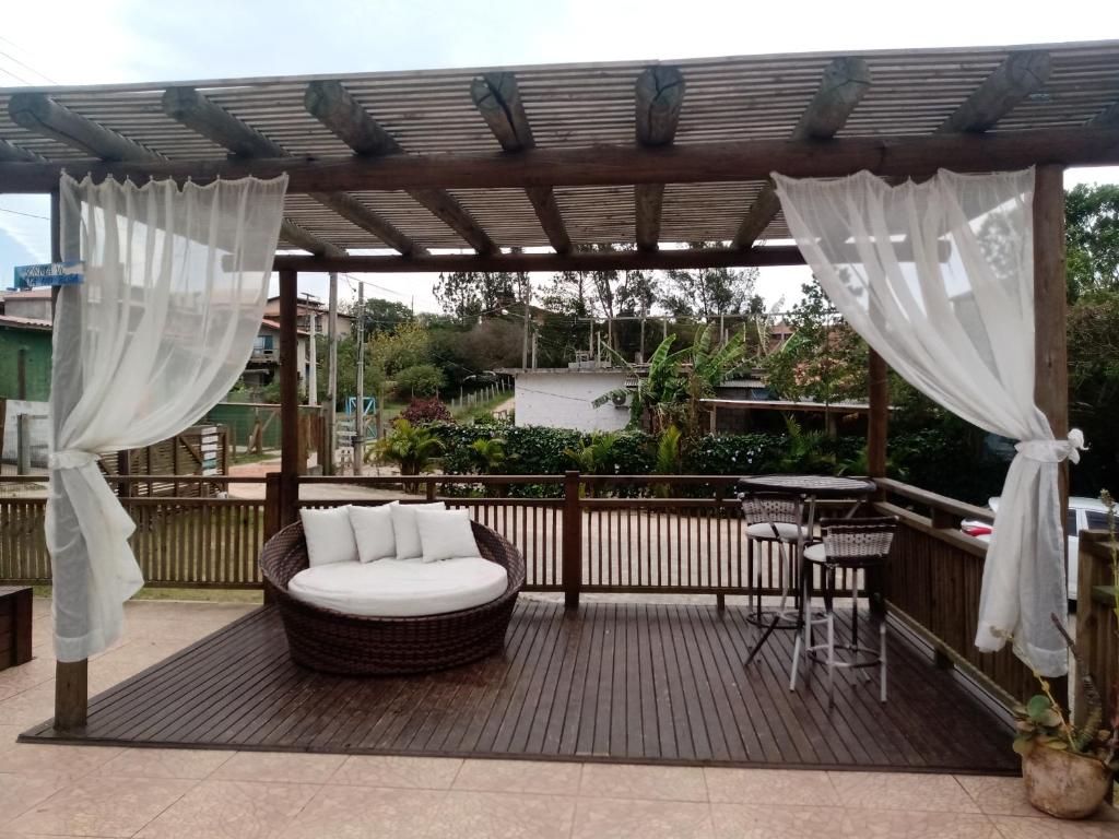 a wooden deck with a pergola and a wicker chair on a patio at Cabanas Alamanda do Rosa in Imbituba
