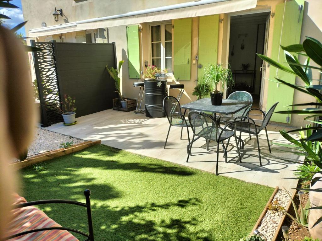 patio ze stołem, krzesłami i trawą w obiekcie Maison dans une résidence de vacances w mieście Gallargues-Le-Montueux