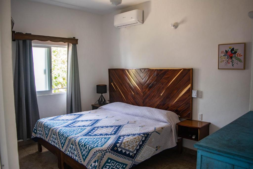 a bedroom with a bed with a wooden headboard and a window at DownTown Rooms San Pancho in San Francisco