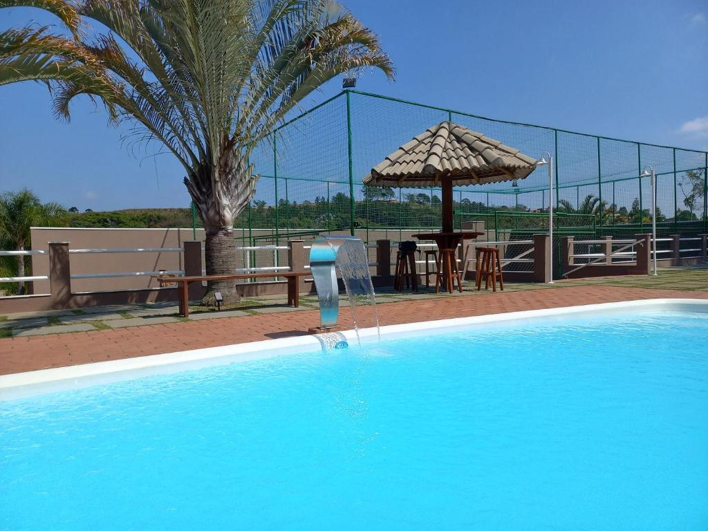 uma piscina com uma mesa e um guarda-sol em Chacara com piscina e muito lazer em Jarinu SP em Jarinu