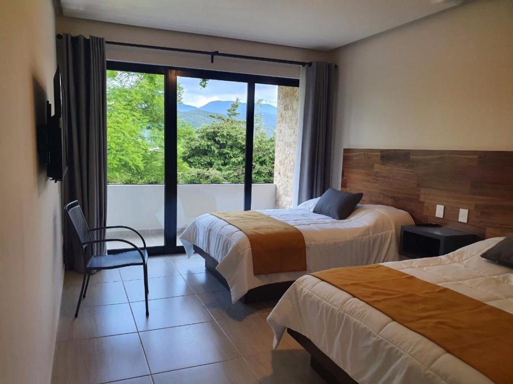 a hotel room with two beds and a large window at Kali Secreto in Jalpan de Serra