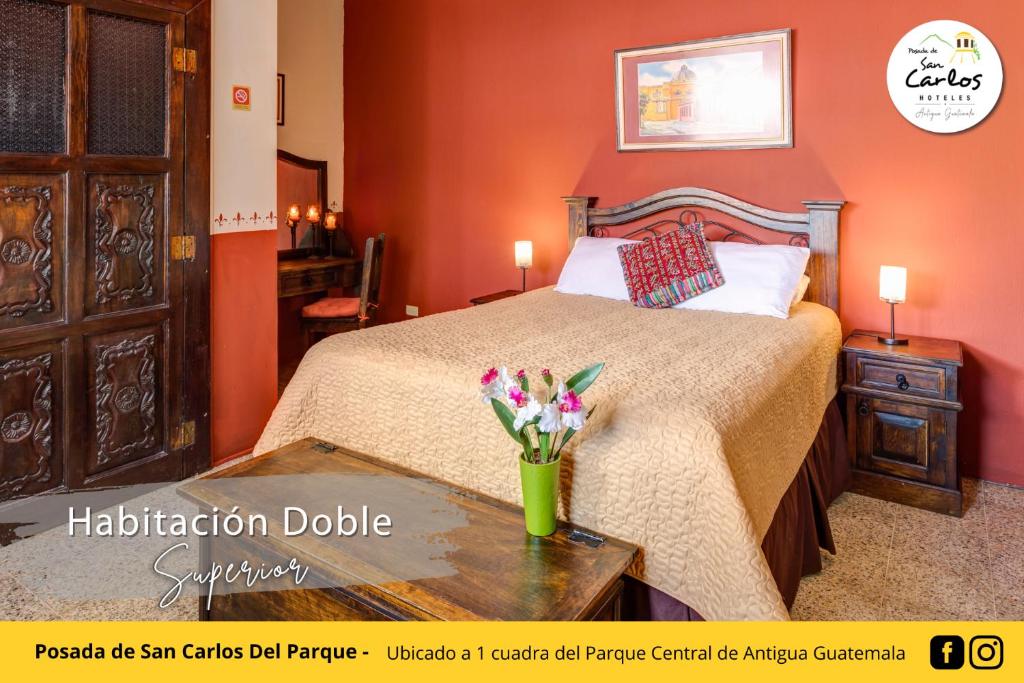 Un dormitorio con una cama y una mesa con flores. en Posada de San Carlos del Parque, en Antigua Guatemala