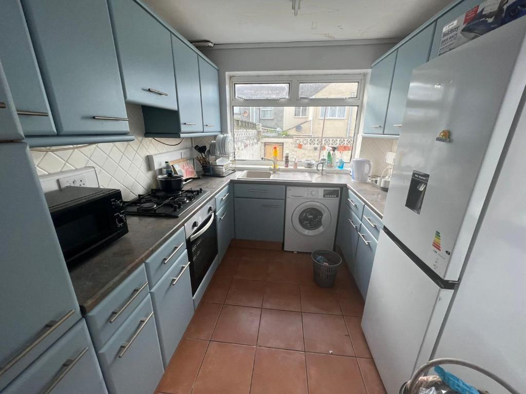 a kitchen with blue cabinets and a washing machine at Cheerful Two Bedrooms Town house with free parking in Pembrokeshire