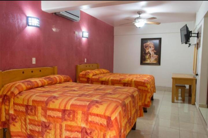 três camas num quarto com paredes vermelhas em HOTEL DEL CENTRO em Ciudad Obregón