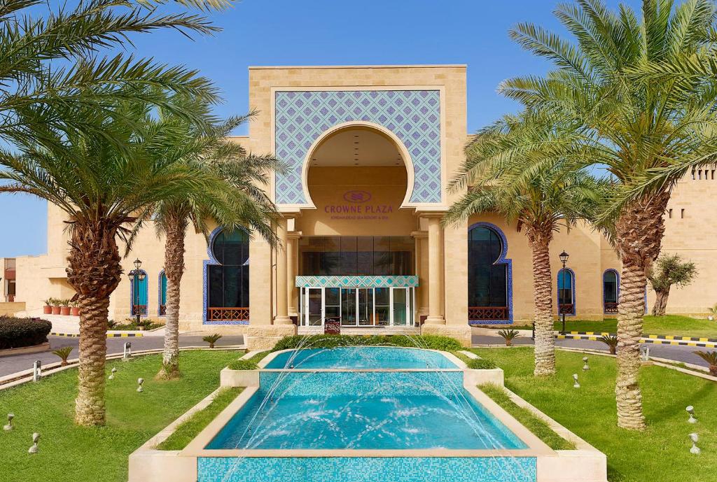 uma piscina em frente a um edifício com palmeiras em Crowne Plaza Jordan Dead Sea Resort & Spa, an IHG Hotel em Sowayma