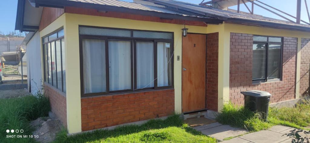 una pequeña casa de ladrillo rojo con puerta marrón en Las Cabañas del Francés, en Vallenar