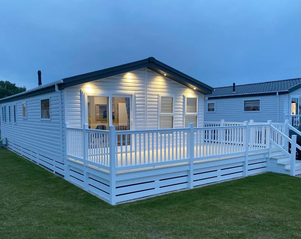 uma casa móvel branca com um grande deque em Sandy Bay Lodge em Newbiggin-by-the-Sea