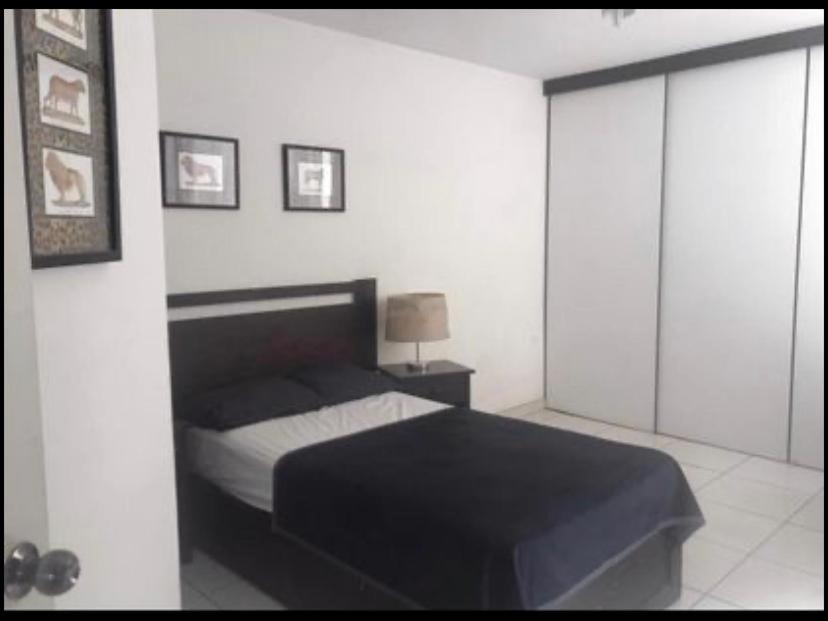 een slaapkamer met een bed in een witte kamer bij Departamento para Turistas - Aeropuerto 20Min in Lima