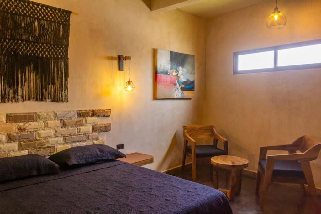 a bedroom with a bed and two chairs and a window at relax hotelito in Cárdenas