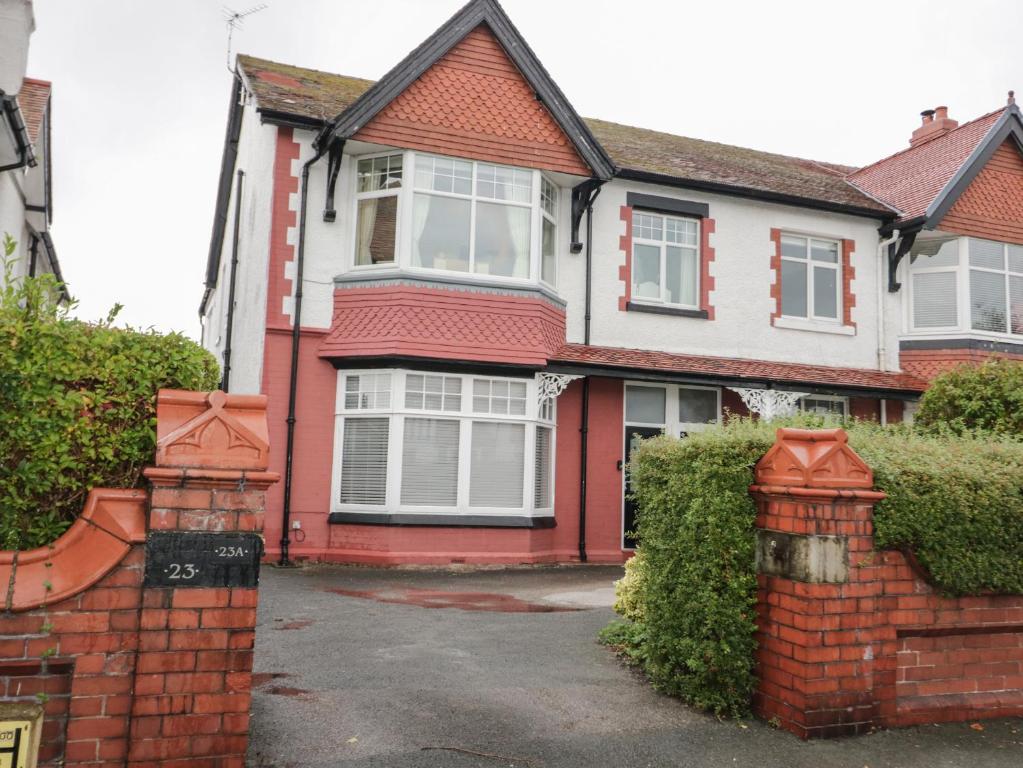 a red and white house with a brick fence at Hafan Y Mor in Rhos-on-Sea