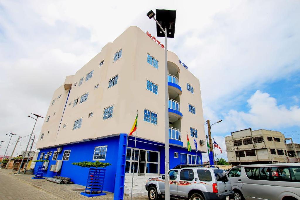a blue and white building with cars parked in front of it at Hotel Galilée in Cotonou