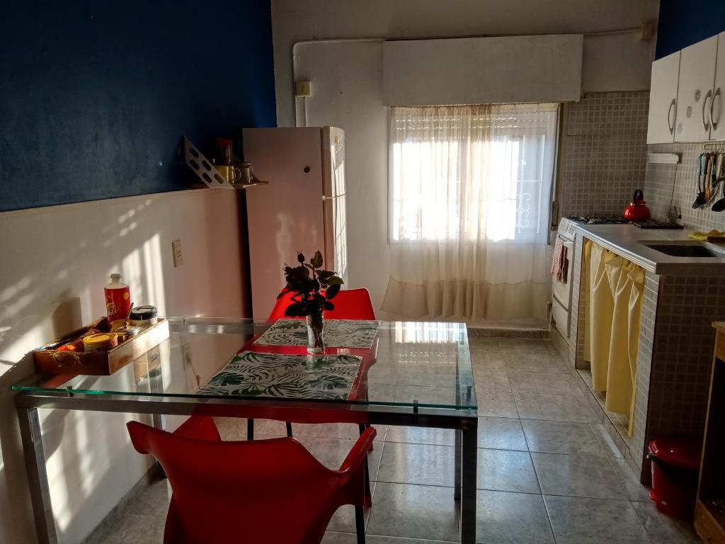 a kitchen with a glass table and red chairs at PUNTO FIJO in Zárate