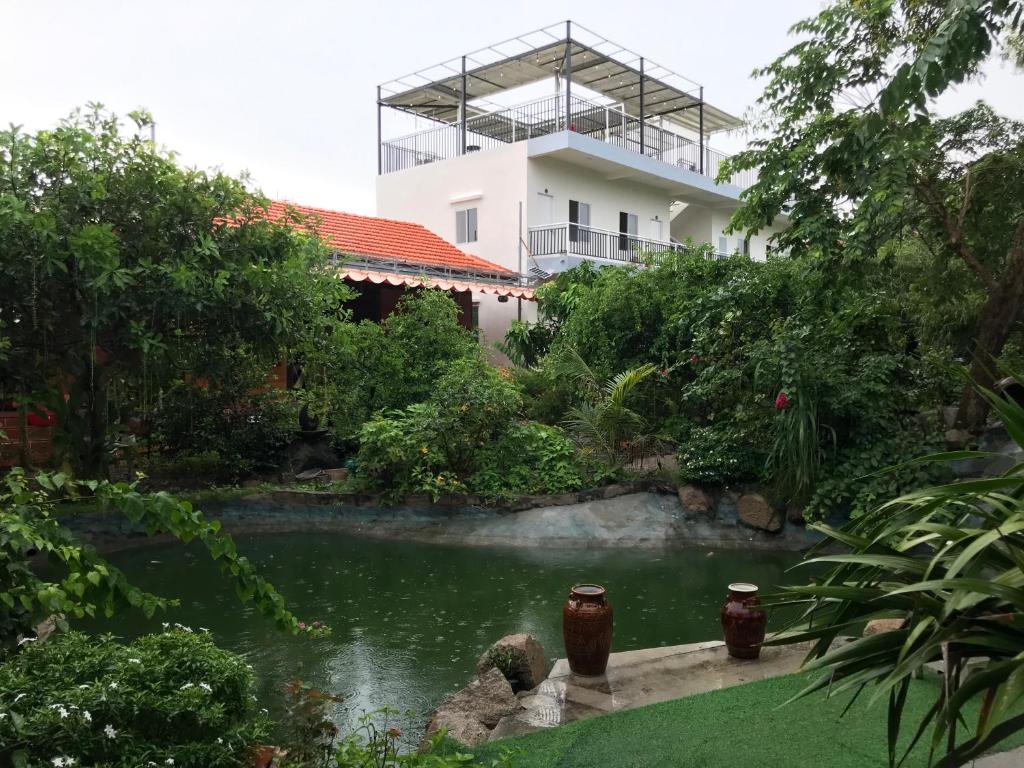 a house with a pond in front of a building at Mộc Lam Homestay in Xóm Chum Găng