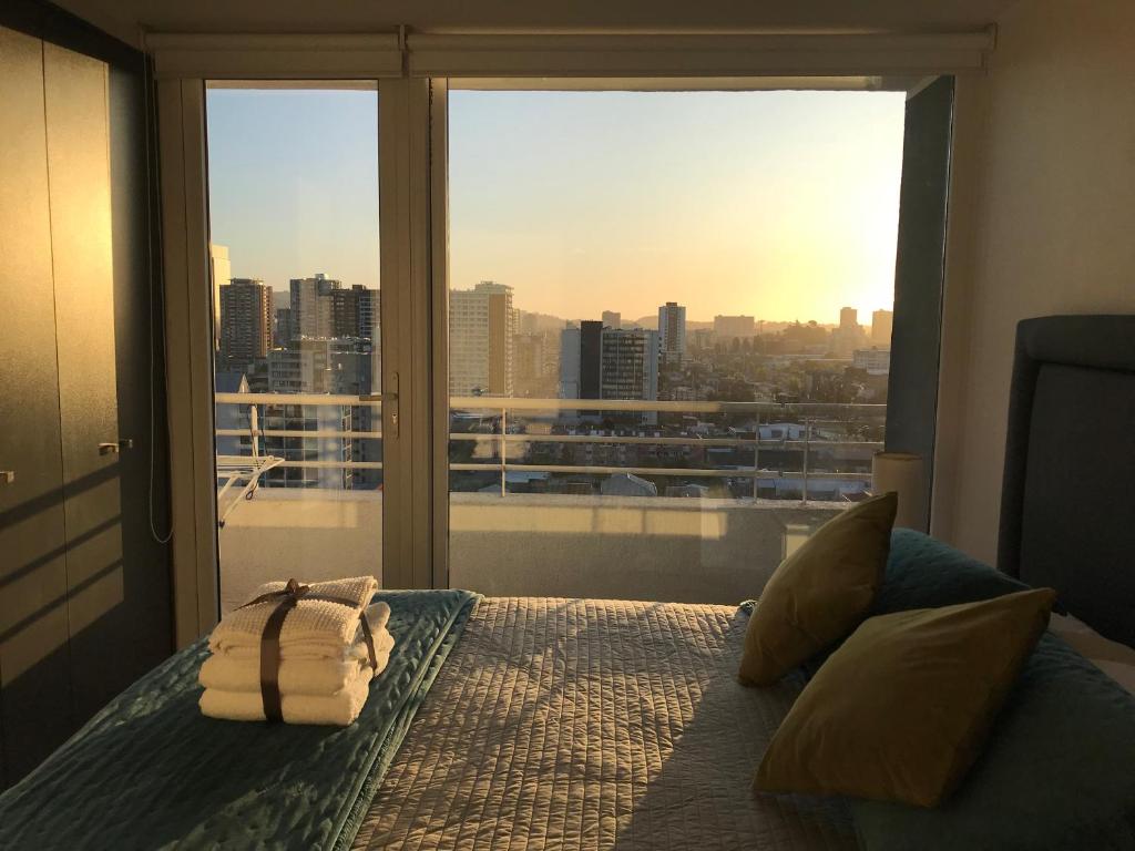 a bedroom with a bed with a view of a city at Elegante y acogedor departamento con gran vista, cercano a todo in Concepción