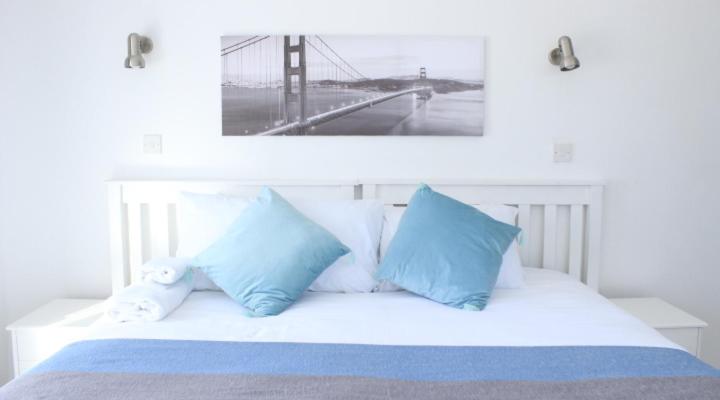 a white bed with blue pillows and a picture of a bridge at Royal relax guest house in Palatswe