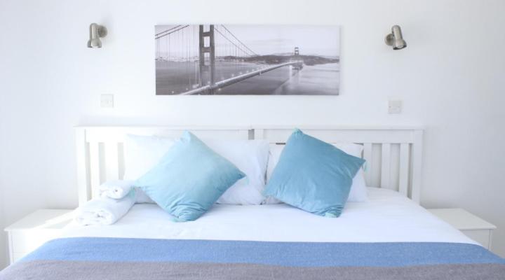een wit bed met blauwe kussens en een afbeelding van een brug bij Royal relax guest house in Palatswe
