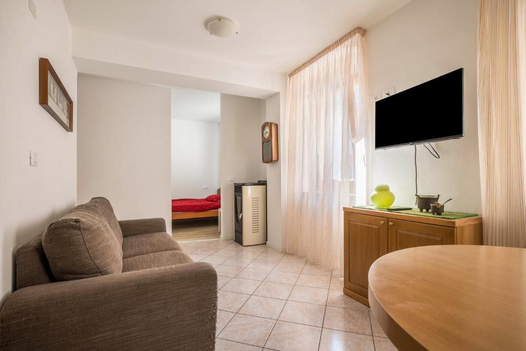 uma sala de estar com um sofá e uma televisão de ecrã plano em Appartamento Meridiana em Roncone