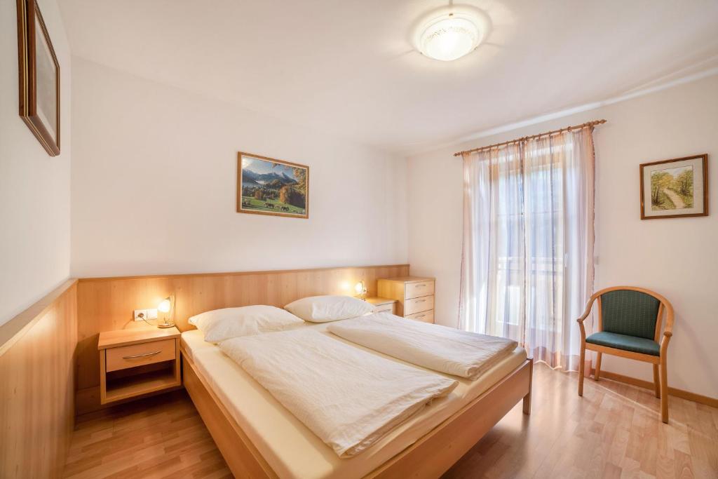 a bedroom with a bed and a chair and a window at Parigger Apt Zirbe in Racines