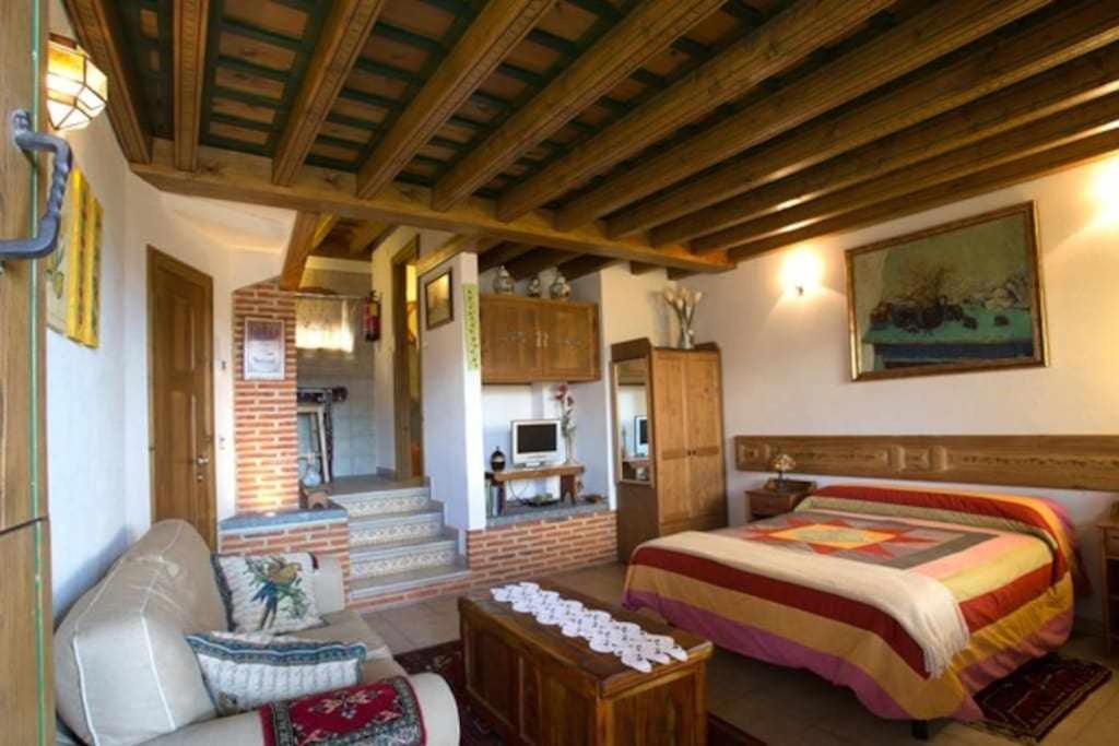 a bedroom with a bed and a living room at Apartamento rural El Pastor es un estudio con gran ventanal a Gredos in Cabezas Bajas