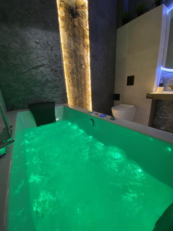 a bath tub with green water in a bathroom at Silver Shine jacuzzi in Krakow