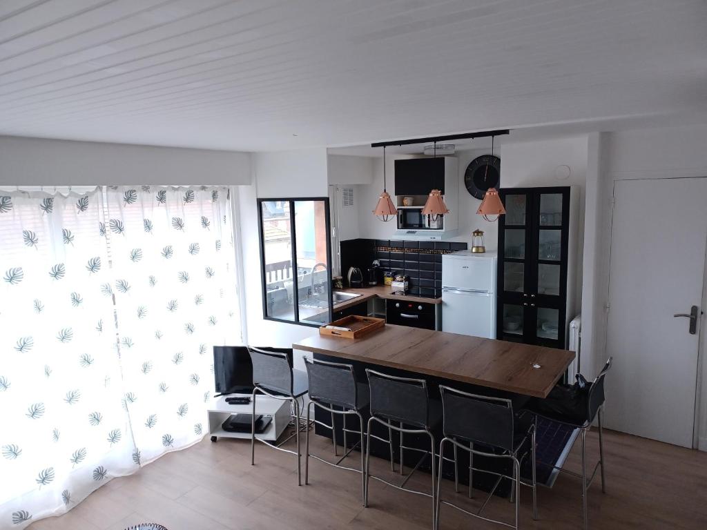 cocina con mesa de madera y sillas negras en Duplex Fossorier - BALCON CENTRE VILLE -, en Deauville