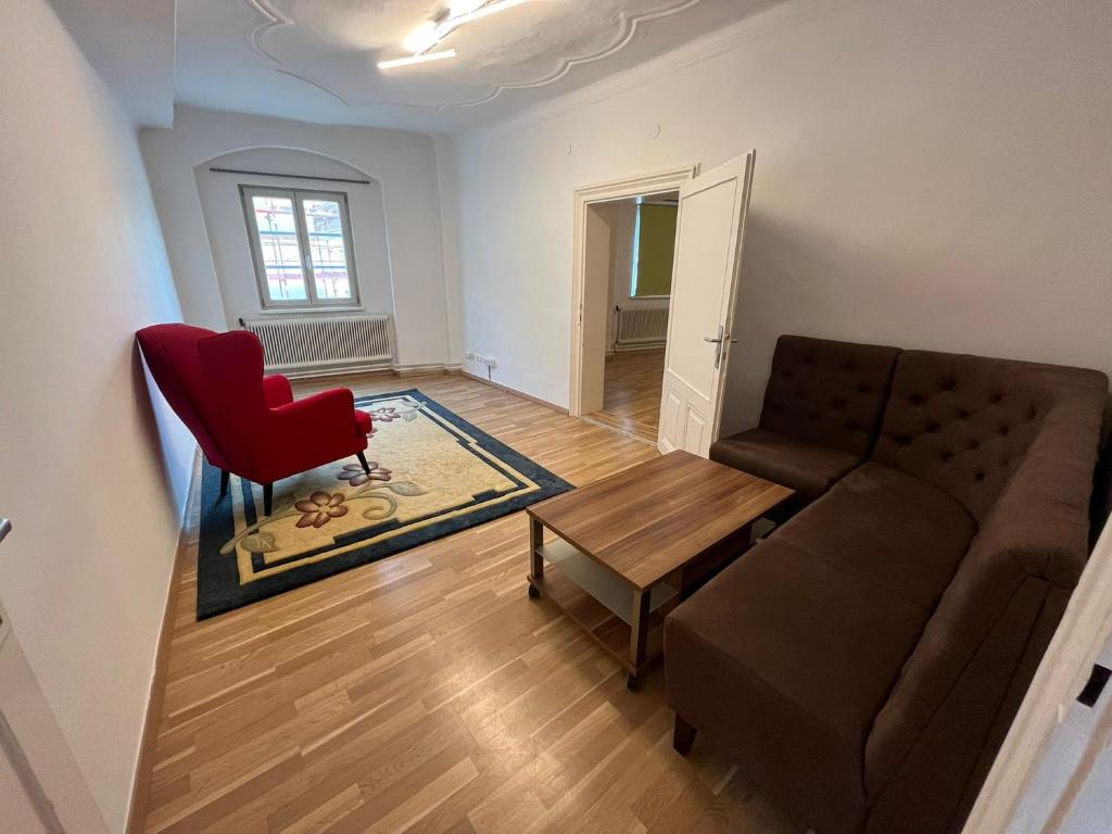 a living room with a couch and a red chair at Hagmann&#39;s Altstadt Appartement in Krems an der Donau