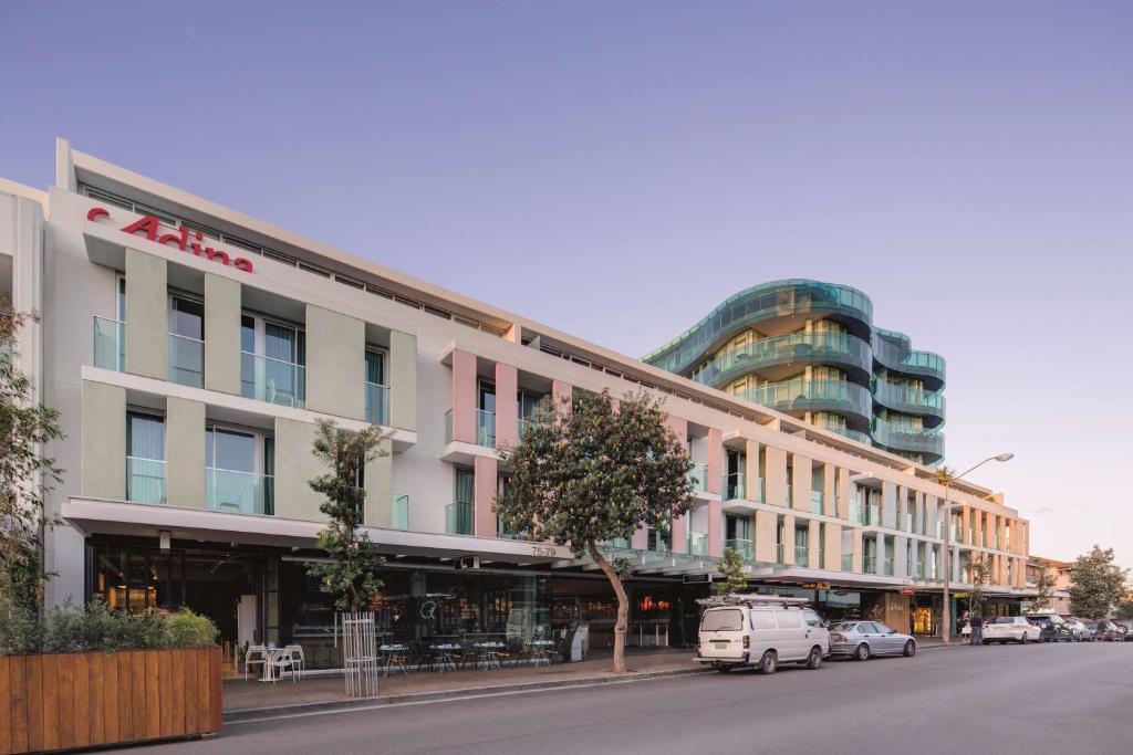 Adina Apartment Hotel Bondi Beach Sydney في سيدني: مبنى على شارع فيه سيارات تقف امامه