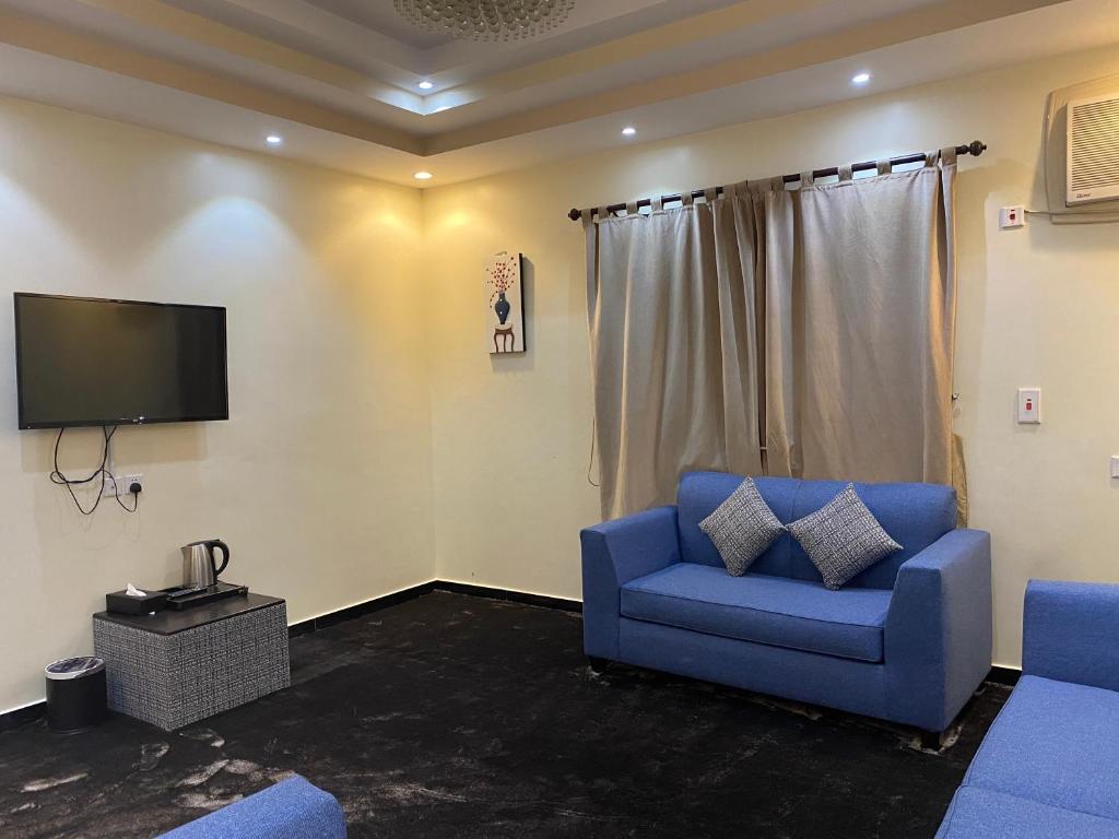 a living room with a blue couch and a tv at ABHASKY in Abha