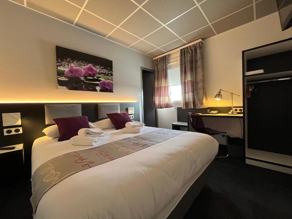 a hotel room with a large bed and a desk at BRIT HOTEL LE VESOUL in Vesoul