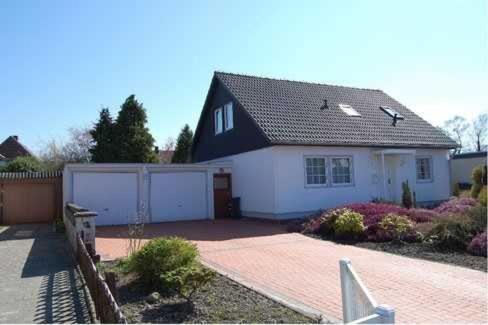 a white house with a black roof and a driveway at Witte Huus 75m_ und 51m_ Ferienwoh in Hooksiel
