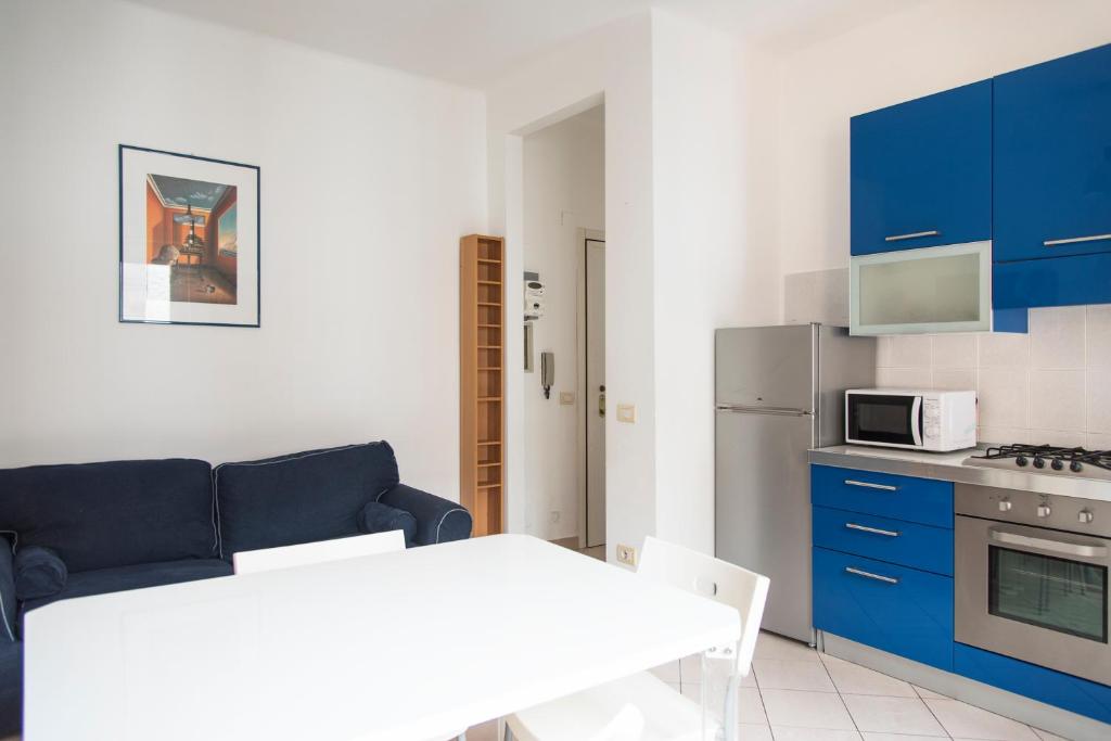 a living room with a blue couch and a kitchen at YouHosty - Metauro 4 in Milan