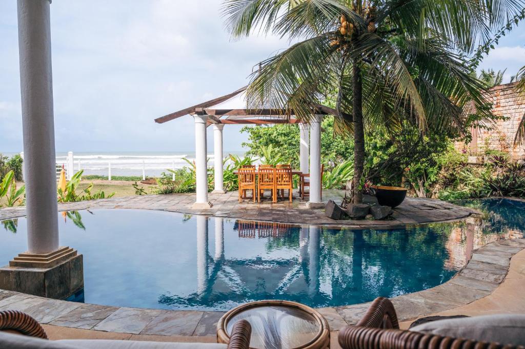 a swimming pool with a gazebo and a palm tree at Sānti Beach House with pool & beach in Weligama