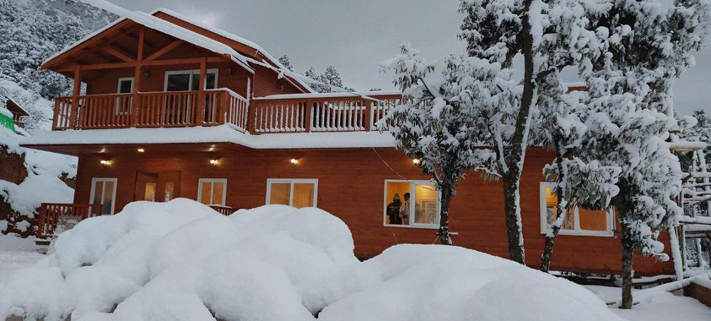 uma cabana de madeira na neve com árvores cobertas de neve em Vanprastha Resorts em Almora