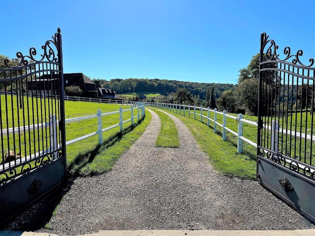 un chemin à travers une clôture blanche dans un champ dans l'établissement Le Gîte Marguerite - Calvados : vue panoramique sur la Normandie, à Hermival-les-Vaux