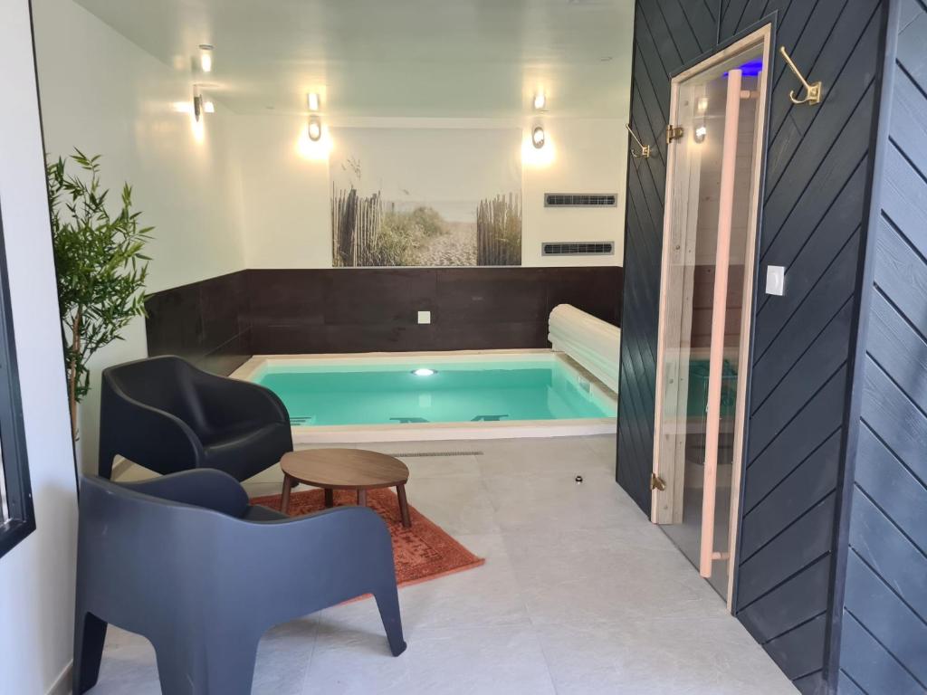 Santec的住宿－Les Suites du Dossen，浴室设有游泳池、椅子和桌子