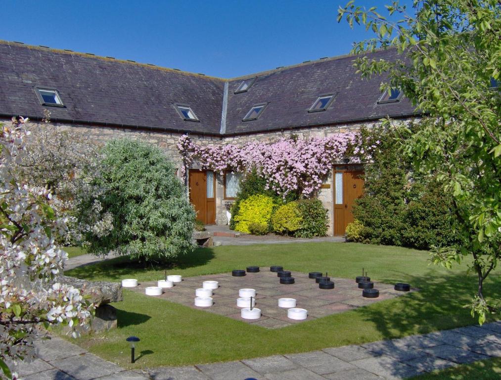 a garden with a table and chairs in front of a building at Carden Holiday Cottages - Elgin in Crook of Alves