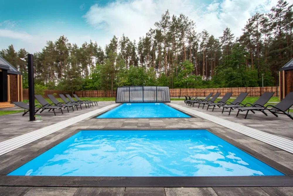 a large swimming pool with chairs and a fence at Złota Szyszka Radawa in Radawa