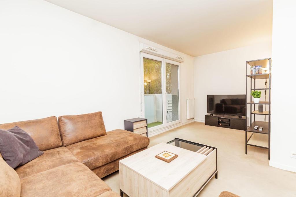 a living room with a couch and a tv at Bright 68 m2 apartment near the Stade de France in Aubervilliers