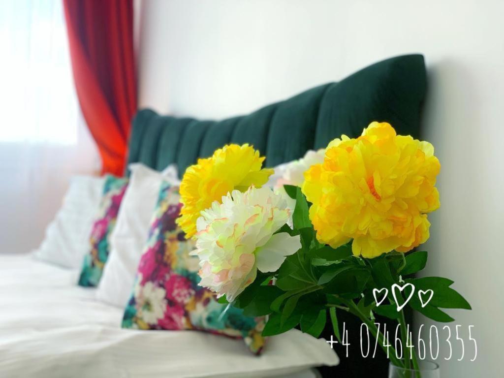 un jarrón lleno de flores amarillas y blancas en un sofá en Red Hotel Accommodation, en Cluj-Napoca