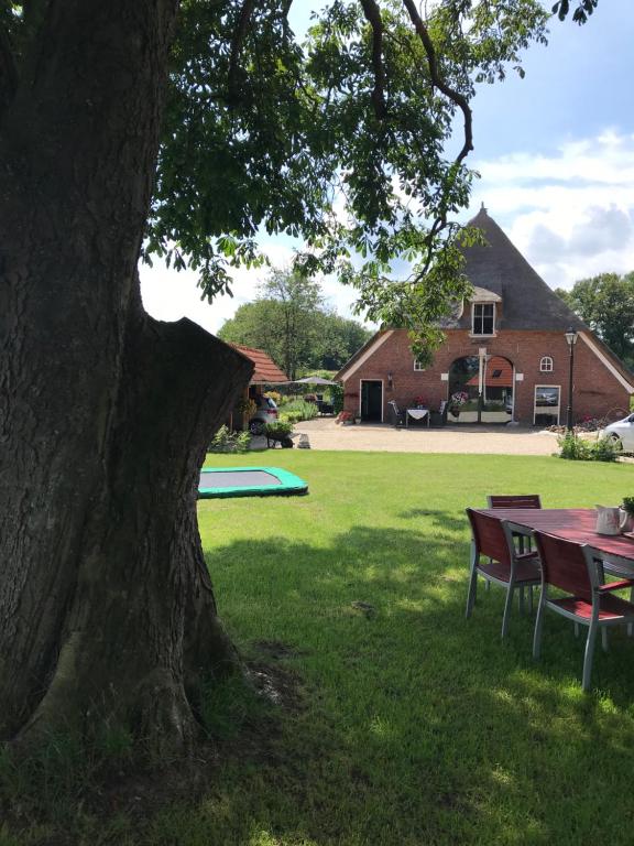 una mesa y sillas bajo un árbol en un patio en Een mooie plek en Markelo