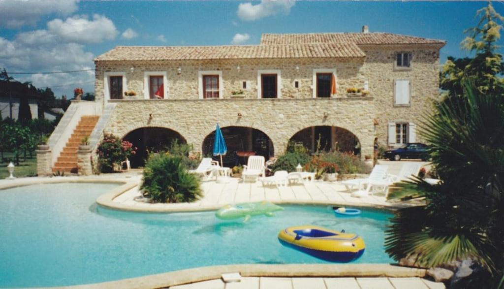 une maison avec une piscine devant une maison dans l'établissement Mas du Garidel l Appartements avec piscine privée proche Ardèche à Saint Julien de Peyrolas, à Saint-Julien-de-Peyrolas