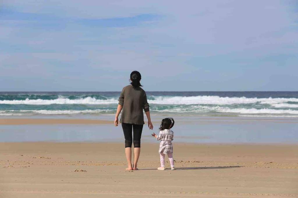 a woman and a child walking on the beach at family friendly 4 bedroom house close to parks in Gold Coast