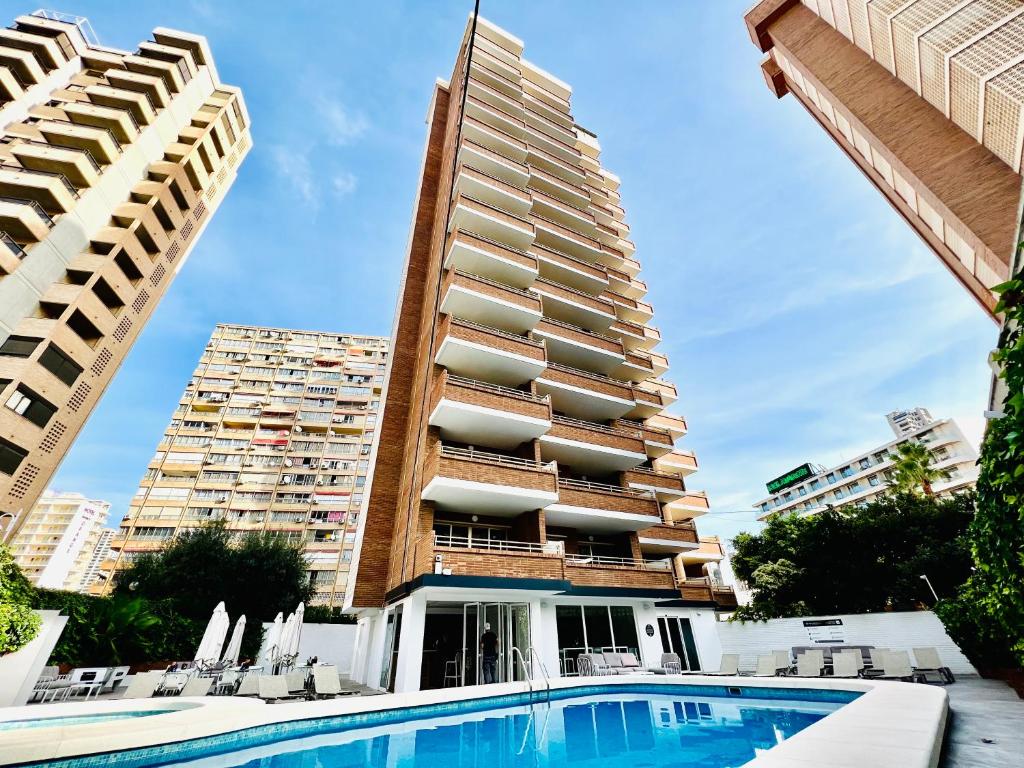 a hotel with a swimming pool in front of a tall building at Trebol One Apartments By Mc in Benidorm