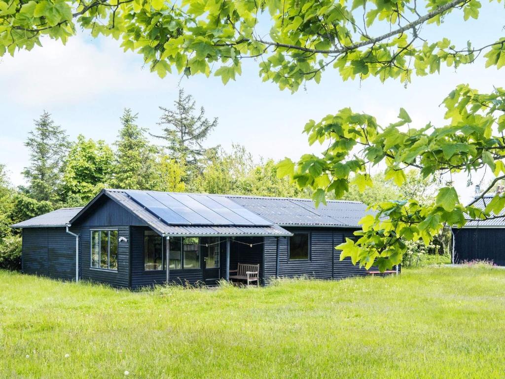 ein schwarzes Haus mit einem Sonnendach auf einem Feld in der Unterkunft 6 person holiday home in Ulfborg in Ulfborg