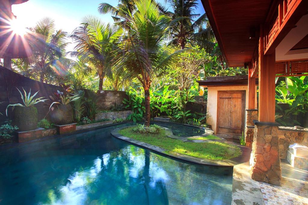 een zwembad voor een huis met palmbomen bij Nidhi Private Villas in Ubud