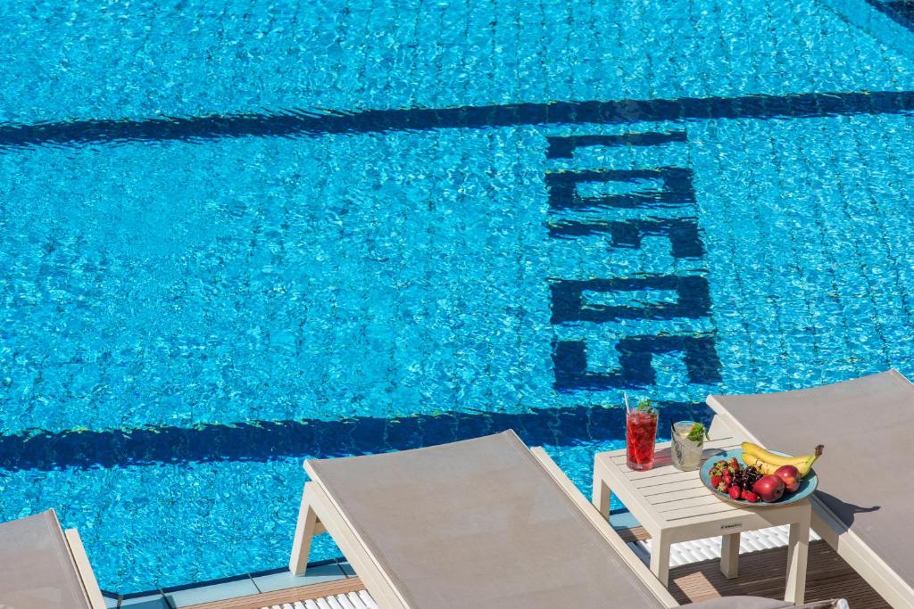 - une piscine avec 2 chaises et un bol de fruits dans l'établissement Lofos Apartments, à Chersónissos