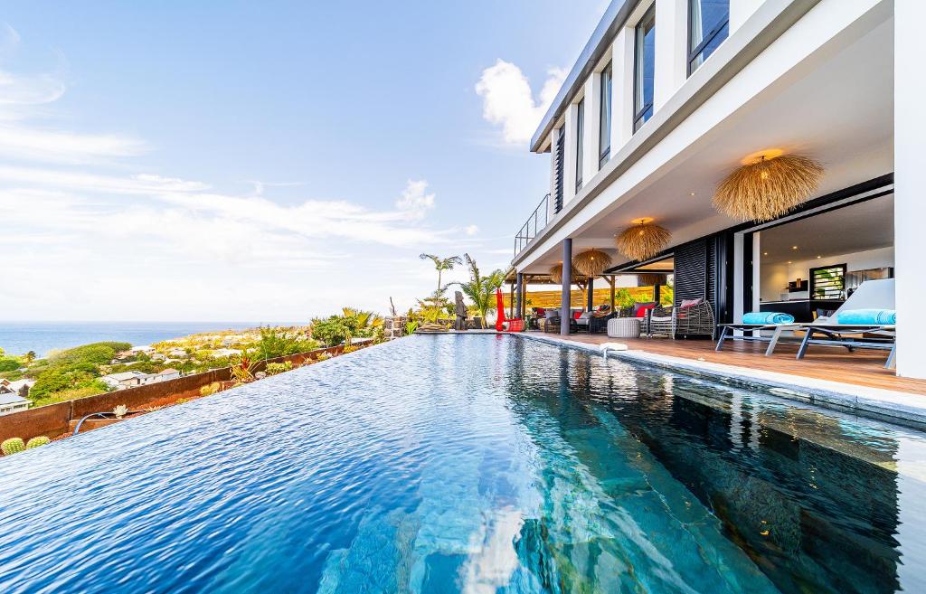 a swimming pool in front of a building with the ocean at Villa Coco Palm ***** in Saint-Pierre
