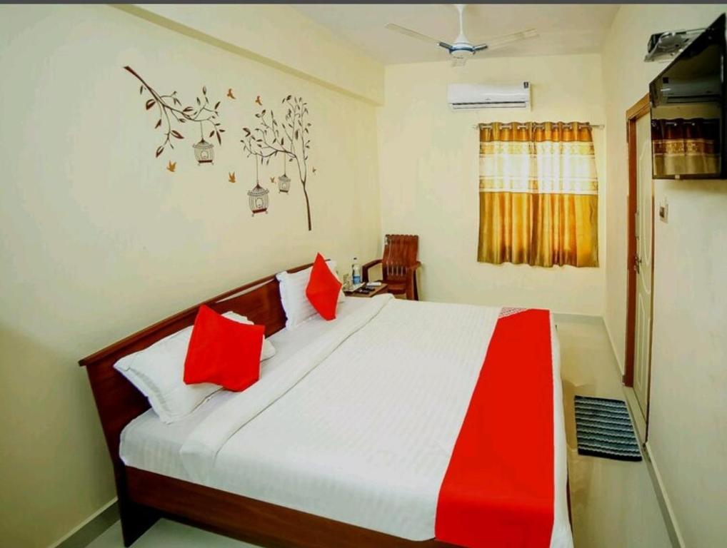 Un dormitorio con una cama con almohadas rojas. en Nandas Grand, en Nellore