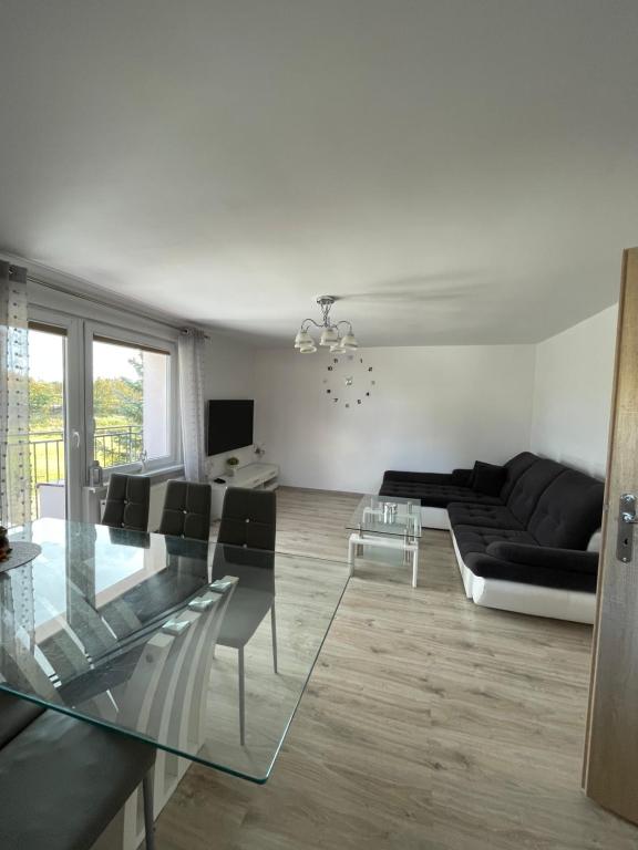uma sala de estar com uma mesa de vidro e um sofá em Apartament NAD CZEREŚNIĄ em Brodnica